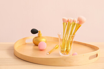 Set of makeup brushes with perfume bottle on table