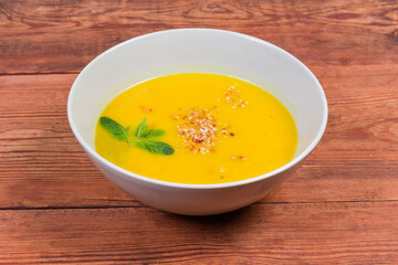 Lentil pumpkin soup puree in bowl on rustic table, closeup