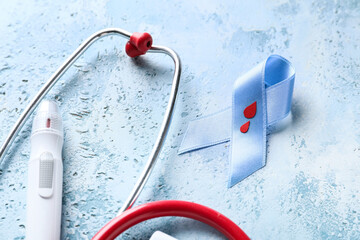 Awareness ribbon with lancet pen and stethoscope on color background. Diabetes concept
