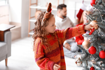 Cute girl decorating Christmas tree at home
