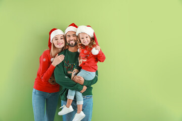 Young family in Santa Claus hats on color background. Christmas celebration