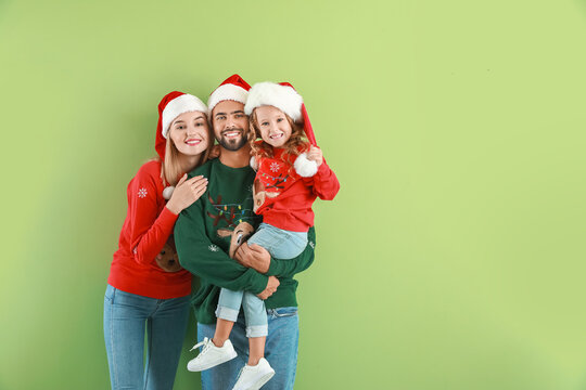 Young family in Santa Claus hats on color background. Christmas celebration - Powered by Adobe