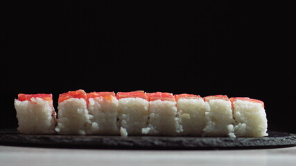 Chef cutting rolls of sushi with a knife on a stone board. - shot at a low angle. Beautiful female...