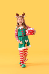 Cute little elf with Christmas gift on color background