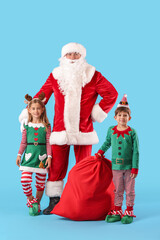 Cute little elves with Santa Claus and bag on color background
