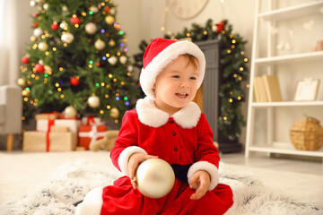 Obraz na płótnie Canvas Cute little baby in Santa costume at home on Christmas eve