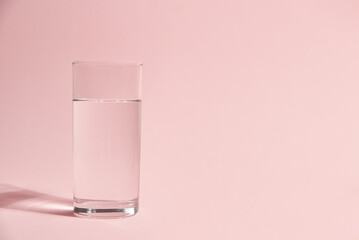 Glass of water on a pink background