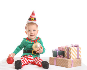 Cute little baby in Christmas elf costume and with gifts on white background