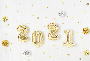 Happy New year 2021 celebration. Gold foil balloons numeral 2021 and gold star on silver background. Flat lay.