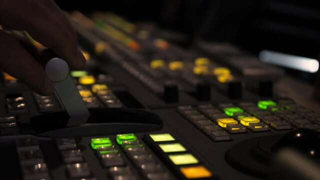 Television director is moving handle on a control panel during tv filming in studio