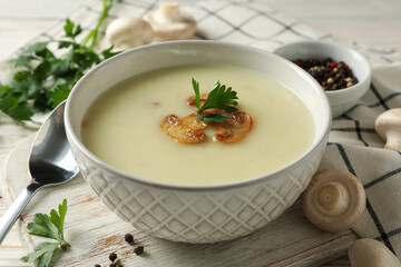 Concept of tasty lunch with bowl of mushroom soup on white wooden background
