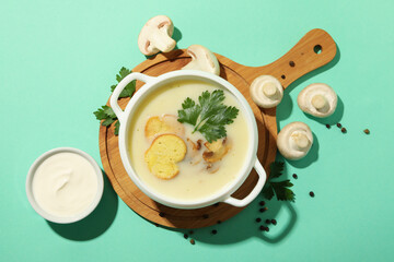 Concept of tasty lunch with bowl of mushroom soup on mint background