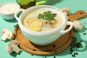Concept of tasty lunch with bowl of mushroom soup on mint background