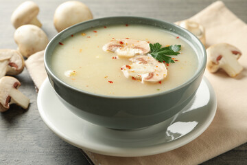 Concept of tasty lunch with bowl of mushroom soup on gray background