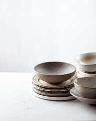 handicraft ceramics, empty craft ceramic bowl and plates on light background 