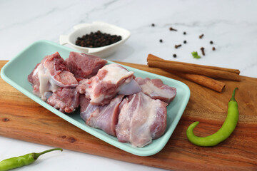 Fresh raw goat meat or mutton or lamb pieces. Preparation for Indian mutton curry. Spice at the background such as cinnamon sticks, red chili powder, black pepper & coriander. Copy space.