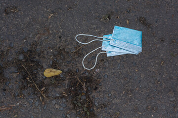 Carelessly discarded medical face mask thrown away on a public footpath during Coronavirus...