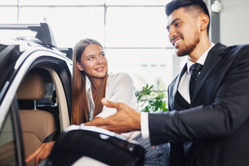 Young attractive woman looking for a new car in a showroom