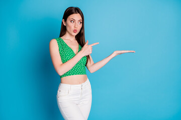 Photo of astonished girl hold hand impressed adverts promotion point index finger copyspace make lips pouted plump wear tank-top pants isolated over blue color background
