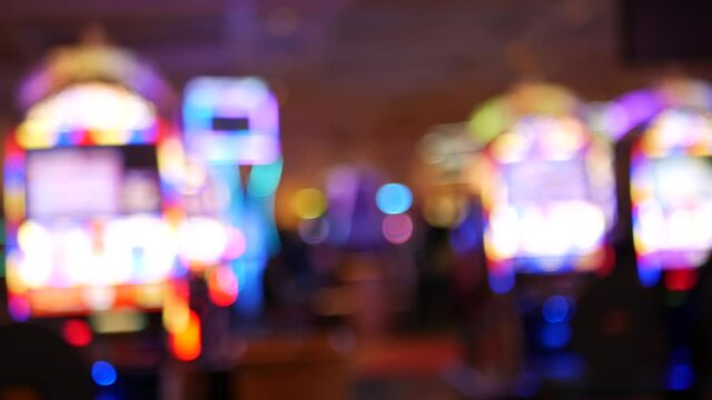 Defocused slot machines glow in casino on fabulous Las Vegas Strip, USA. Blurred gambling jackpot slots in hotel near Fremont street. Illuminated neon fruit machine for risk money playing and betting.