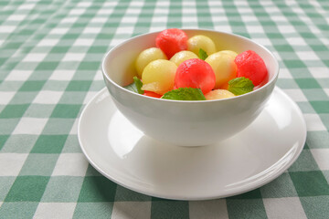 Watermelon granita ice cream. Melon and watermelon sorbet ice cream balls in a white bowl over green plaid table cloth.