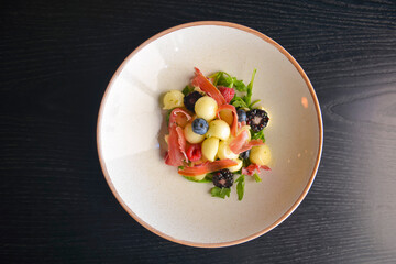 Salad of mixed summer berries. Seasonal summer salad with fruit and berries and Italian prosciutto meat.