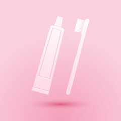 Paper cut Tube of toothpaste and toothbrush icon isolated on pink background. Paper art style. Vector.