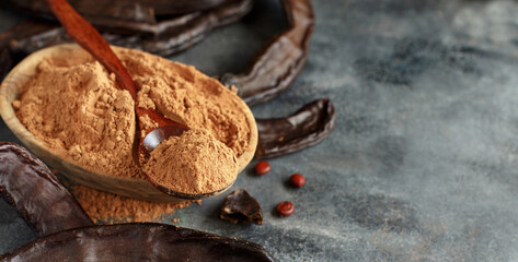 Dry carob pods and powder close up