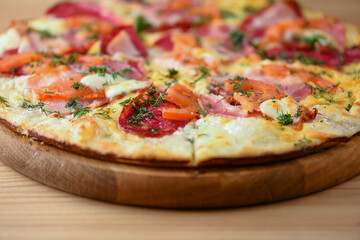 Fresh pizza with tomatoes, cheese and mushrooms on wooden board over rustic wooden table background closeup.