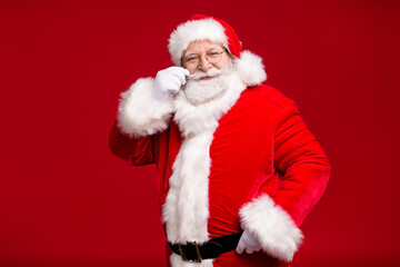 Photo of pensioner old man grey beard hand hip gentleman play curl flirting snow maiden wear santa costume leather belt gloves coat spectacles headwear isolated red color background