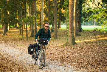 Fototapeta na wymiar Hipster man pushing a bicycle at a public park during autumn.