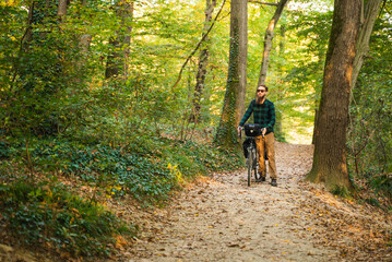 Attractive hipster man with bicycle at a public park during autumn.