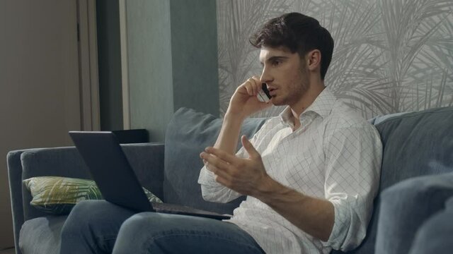 Confident man using laptop phone same time. Guy working with smartphone computer