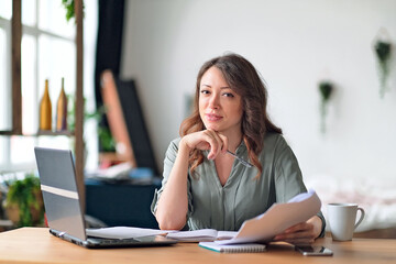 Young woman working from home office. Freelancer using laptop and the Internet. Workplace in living...