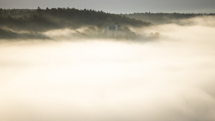 Naklejka premium Fog and mist covering Blaubeuren with the castle Rusenschloss on the mountain
