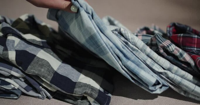 Women's hands sort through a stack of men's shirts