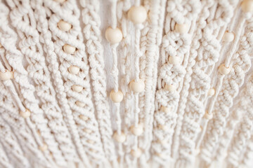 Close-up of hand made macrame texture pattern. Eco friendly modern knitting. Natural decoration concept in the interior. Handmade macrame wall hanging 100% cotton and wooden beads. Soft fokus