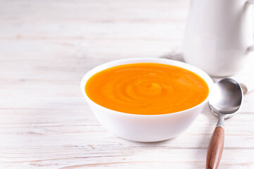 Traditional autumn and winter dishes, hot and spicy pumpkin soup on a white table, copy space