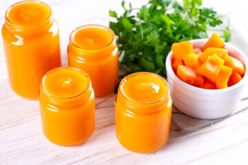 Natural baby food concept. Vegetable puree in bowl on white wooden background near ingredients....