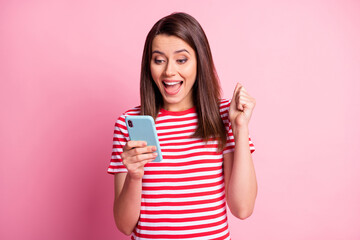 Photo of astonished nice young brunette lady look gadget wear casual outfit isolated over pastel pink background