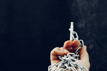 Male hand in metal chains holding cigarette