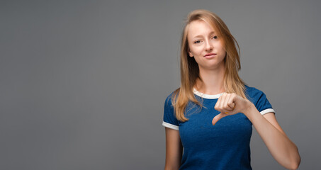 Beautiful young female looking is upset at the camera, holding thumb down. Concept of dislike