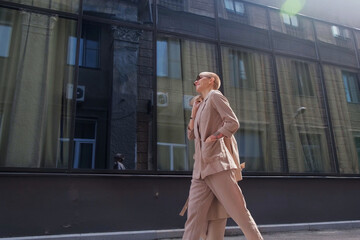 Obraz premium Smart attractive woman with short hair. A businesswoman using her smartphone and smiles on a city street.