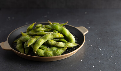 Japanese appetizer Edamame green soybeans seasoned with salt in a bowl, with shop sticks on the side.