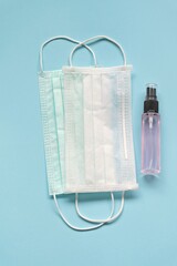 Medical face mask and alcohol spray bottle on blue background. Essential item people need to protection covid-19 disease.