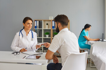 Fototapeta premium The doctor gives the patient a prescription while sitting at the table in the office of the clinic.Medical consultation.