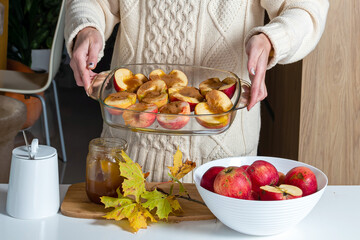 a woman holds in her hands glass container with apples prepared for baking
