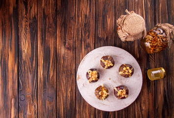 Fototapeta na wymiar Ripe figs baked with cow's-milk cheese brie and camambert and sprinkled with bread crumbs, jars of honey with nuts on wooden background. Healthy eating concept. top view. copy space