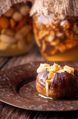 Ripe figs baked with cow's-milk cheese brie and camambert and sprinkled with bread crumbs on vintage cooper plate. Jars of honey with nuta on backdrop. Healthy eating concept.