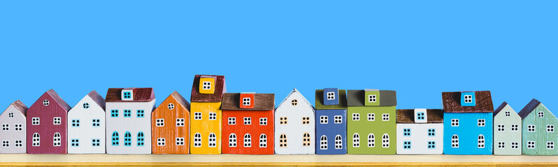 Row of wooden miniature colorful retro houses on blue solid background - 386340640